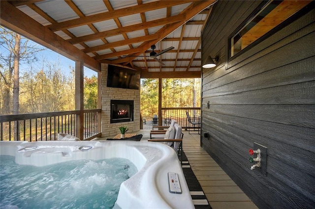 wooden terrace featuring ceiling fan, a hot tub, and exterior fireplace