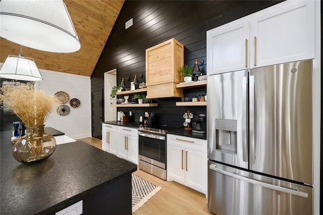 kitchen featuring white cabinets, wooden walls, vaulted ceiling, appliances with stainless steel finishes, and wood ceiling