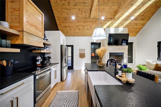 kitchen featuring appliances with stainless steel finishes, light wood-type flooring, wood ceiling, vaulted ceiling with beams, and white cabinetry