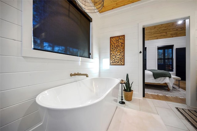 bathroom with tile patterned floors, a tub, and wood walls