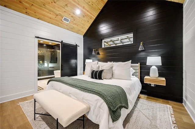 bedroom featuring wood walls, a barn door, light wood-type flooring, and wood ceiling