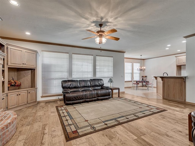 living room with ceiling fan with notable chandelier, ornamental molding, and light hardwood / wood-style flooring