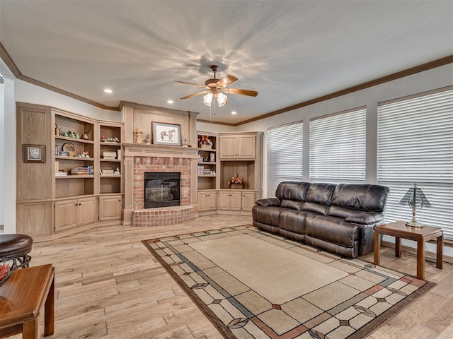 living room featuring a fireplace, light hardwood / wood-style floors, ceiling fan, and ornamental molding