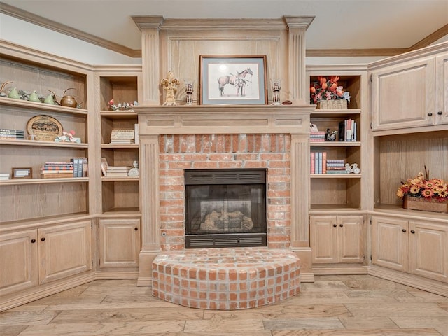 living room featuring built in shelves, light hardwood / wood-style floors, a brick fireplace, and crown molding