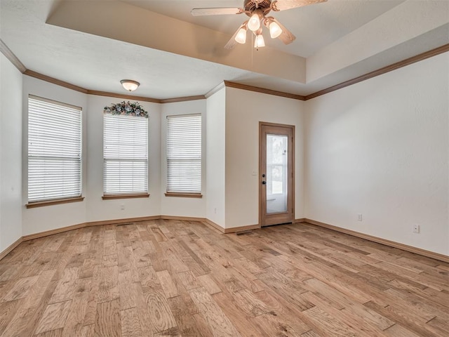 foyer with ceiling fan, a raised ceiling, ornamental molding, and light hardwood / wood-style flooring