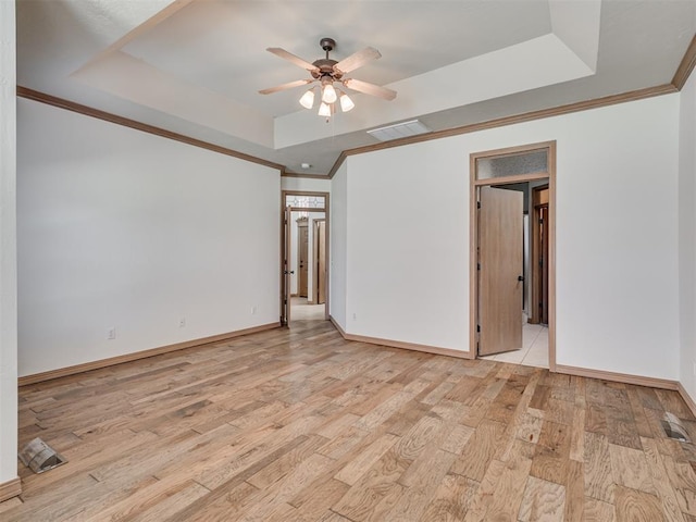 unfurnished room with a tray ceiling, ceiling fan, light hardwood / wood-style floors, and ornamental molding