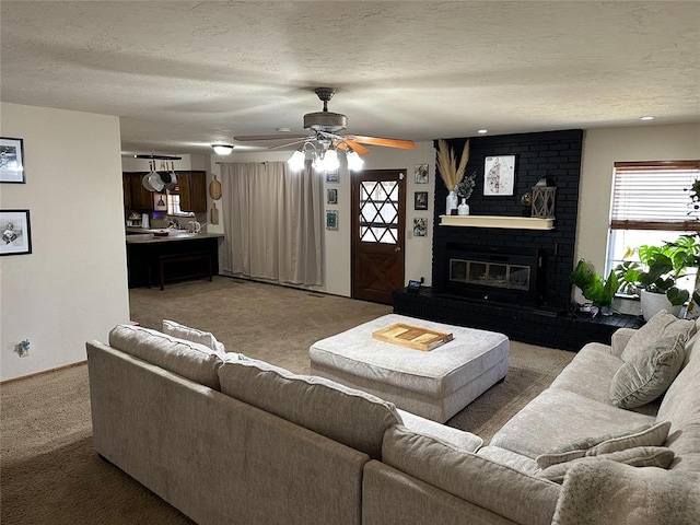 living room featuring a textured ceiling, carpet floors, a brick fireplace, and ceiling fan