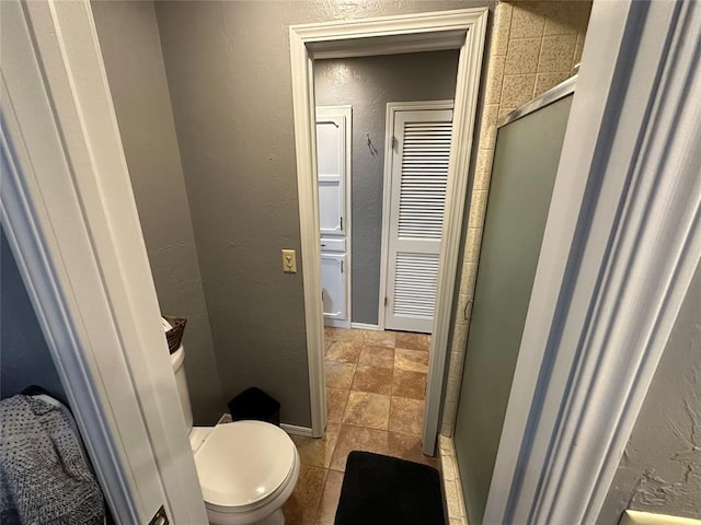 bathroom with a shower with shower door and toilet