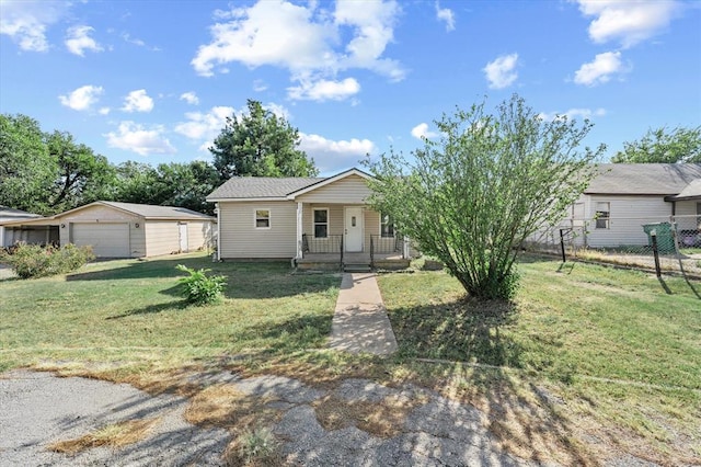 view of front facade featuring an outbuilding, covered porch, a front yard, and a garage