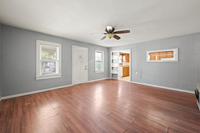 unfurnished living room with ceiling fan, plenty of natural light, a textured ceiling, and hardwood / wood-style flooring