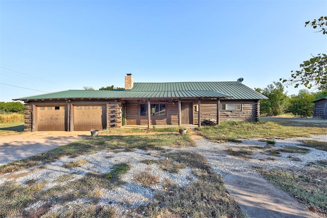 log cabin featuring covered porch and a garage