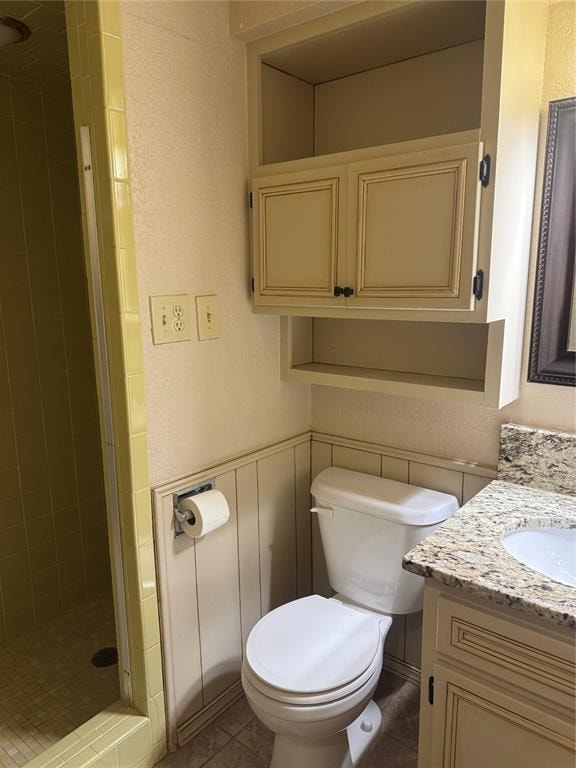 bathroom featuring tile patterned floors, vanity, toilet, and walk in shower