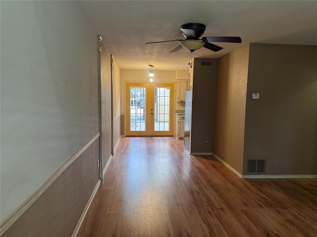 unfurnished room with french doors, ceiling fan, hardwood / wood-style floors, and a textured ceiling