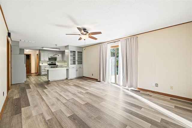 unfurnished living room with ceiling fan, light wood-type flooring, and a textured ceiling