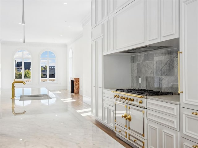 kitchen with hardwood / wood-style floors, stainless steel gas stovetop, crown molding, tasteful backsplash, and light stone counters