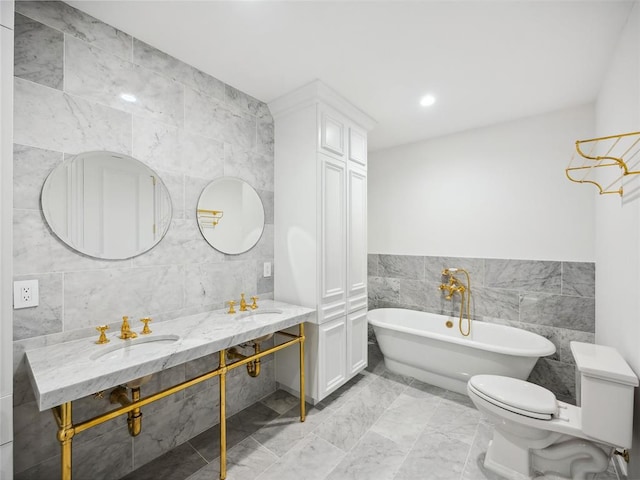 bathroom with a tub, sink, tile walls, and toilet