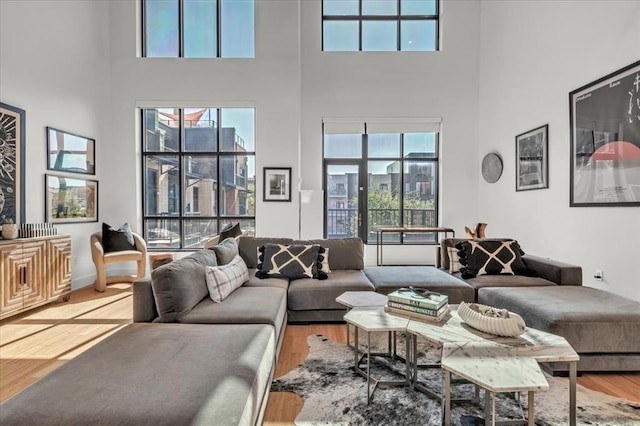 living room with a wealth of natural light, a towering ceiling, and wood-type flooring