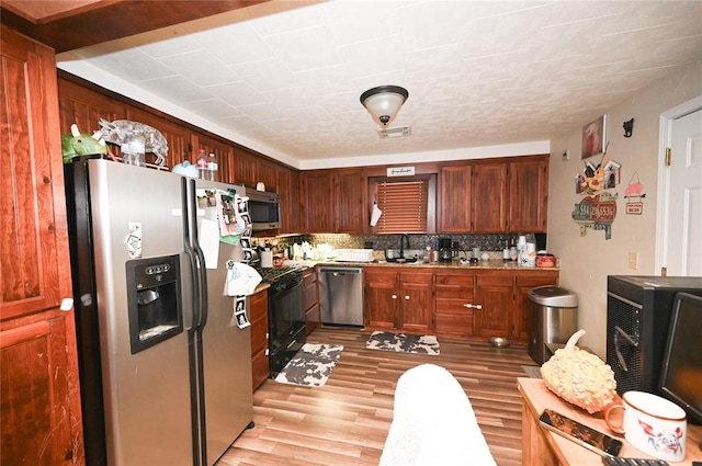 kitchen featuring tasteful backsplash, sink, light hardwood / wood-style floors, and appliances with stainless steel finishes