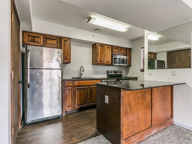 kitchen featuring kitchen peninsula, dark hardwood / wood-style flooring, stainless steel appliances, and sink