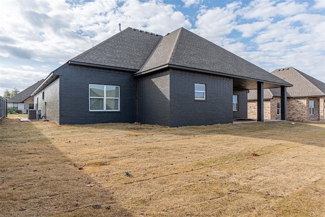 11601 SW 58th St, Mustang, OK 73064 - back of property with a shingled roof, brick siding, a lawn, and central air condition unit