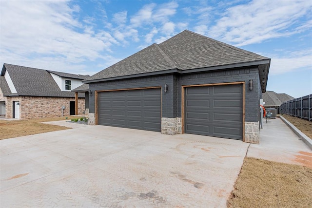 11601 SW 58th St, Mustang, OK 73064 - view of front facade featuring roof with shingles, driveway, a garage, and stone siding