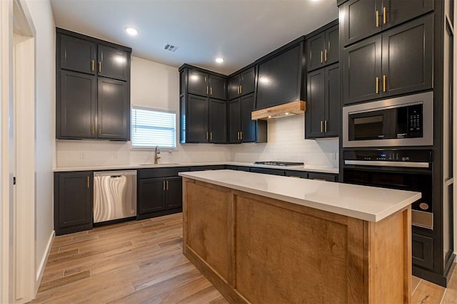 11601 SW 58th St, Mustang, OK 73064 - kitchen with appliances with stainless steel finishes, a sink, light wood-style flooring, decorative backsplash, and light countertops