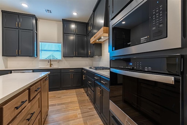 11601 SW 58th St, Mustang, OK 73064 - kitchen with stainless steel appliances, a sink, decorative backsplash, light countertops, and light wood-type flooring