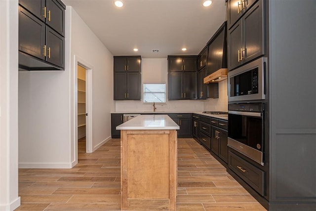 11601 SW 58th St, Mustang, OK 73064 - kitchen with appliances with stainless steel finishes, a sink, light wood-style floors, a kitchen island, and light countertops