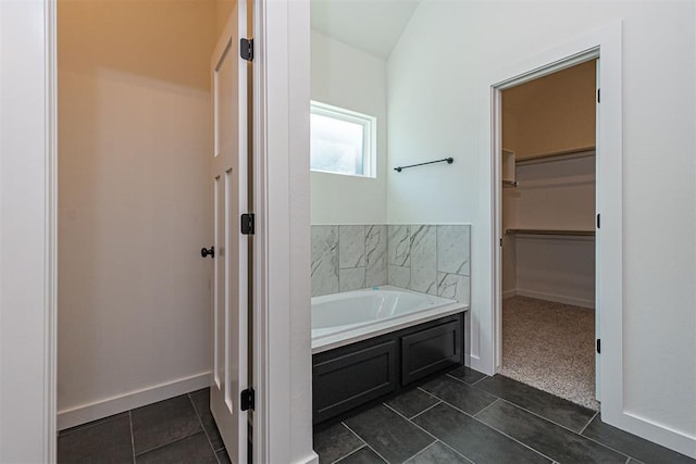 11601 SW 58th St, Mustang, OK 73064 - bathroom with a walk in closet, a garden tub, tile patterned flooring, and baseboards