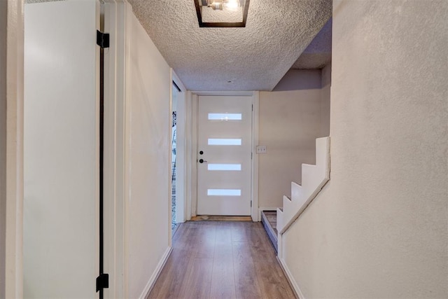 doorway with a textured ceiling and hardwood / wood-style floors