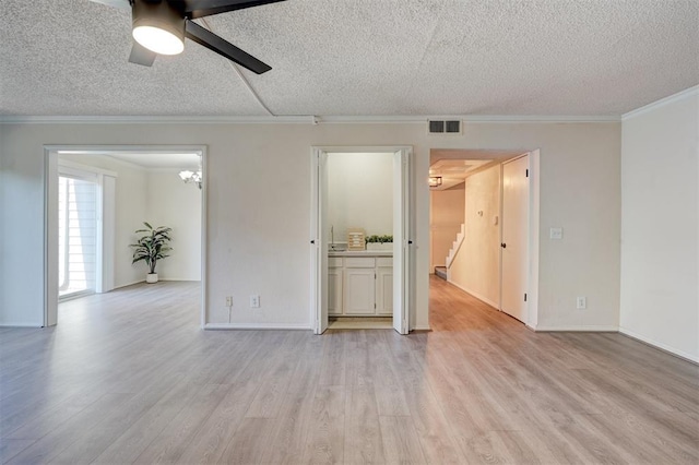 spare room featuring ornamental molding, ceiling fan with notable chandelier, a textured ceiling, and light wood-type flooring