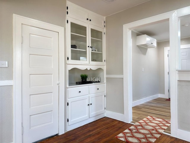 interior space with dark hardwood / wood-style floors and white cabinetry