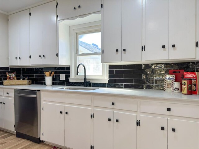 kitchen with sink, light hardwood / wood-style flooring, stainless steel dishwasher, decorative backsplash, and white cabinetry