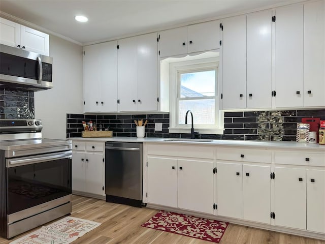 kitchen featuring stainless steel appliances, white cabinetry, tasteful backsplash, and light hardwood / wood-style flooring