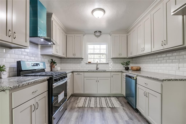 kitchen featuring sink, wall chimney exhaust hood, stainless steel appliances, backsplash, and light hardwood / wood-style floors