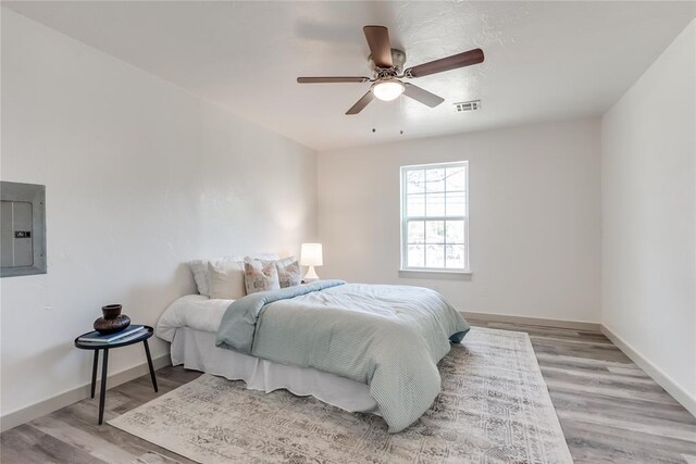 bedroom with ceiling fan, light hardwood / wood-style floors, and electric panel