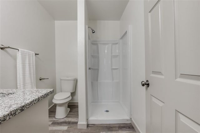 bathroom featuring a shower, hardwood / wood-style floors, vanity, and toilet