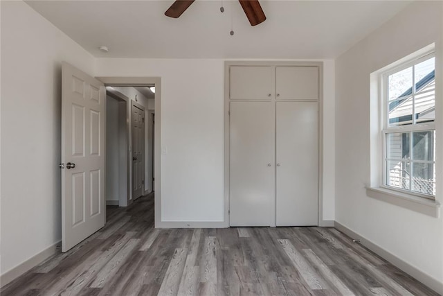 unfurnished bedroom featuring ceiling fan, a closet, and light wood-type flooring