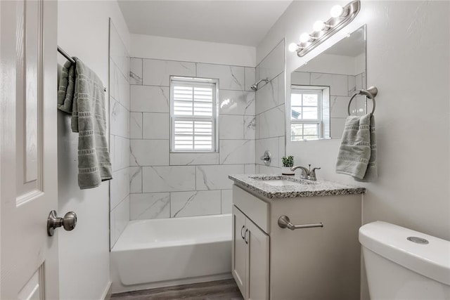 full bathroom with vanity, hardwood / wood-style flooring, toilet, and tiled shower / bath