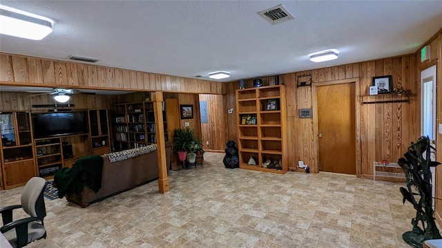 interior space featuring ceiling fan and wooden walls