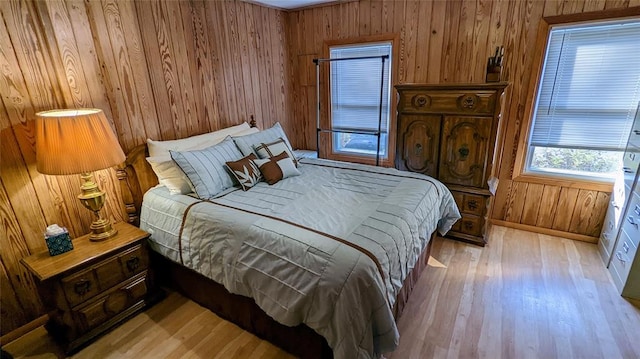 bedroom with light hardwood / wood-style floors and wood walls