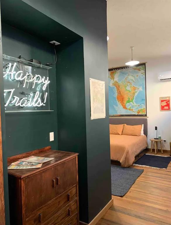 bedroom featuring a wall mounted AC and hardwood / wood-style floors