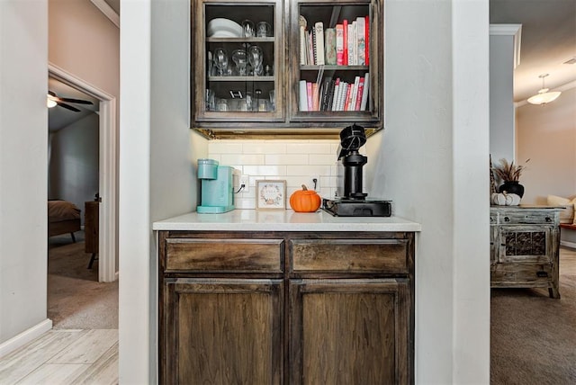 bar featuring light carpet, decorative backsplash, ceiling fan, and crown molding