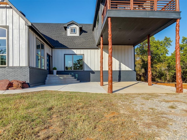 rear view of property featuring a patio area, a yard, and a balcony