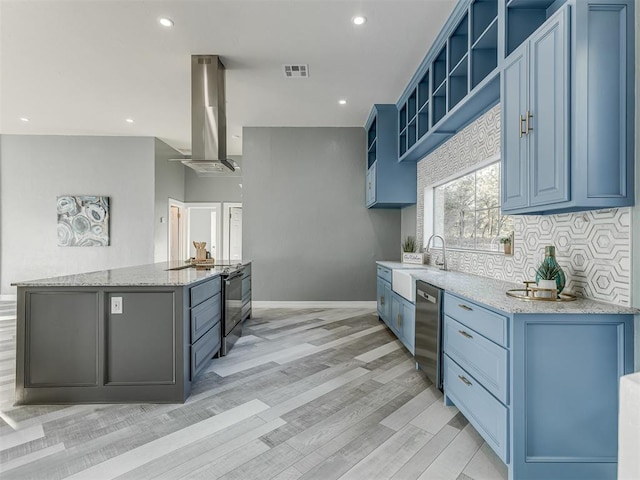 kitchen with wall chimney range hood, sink, light hardwood / wood-style flooring, light stone countertops, and appliances with stainless steel finishes