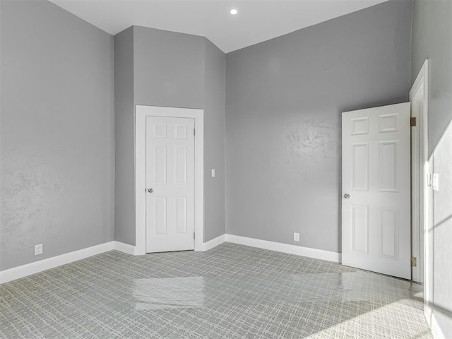 spare room with a high ceiling and light colored carpet