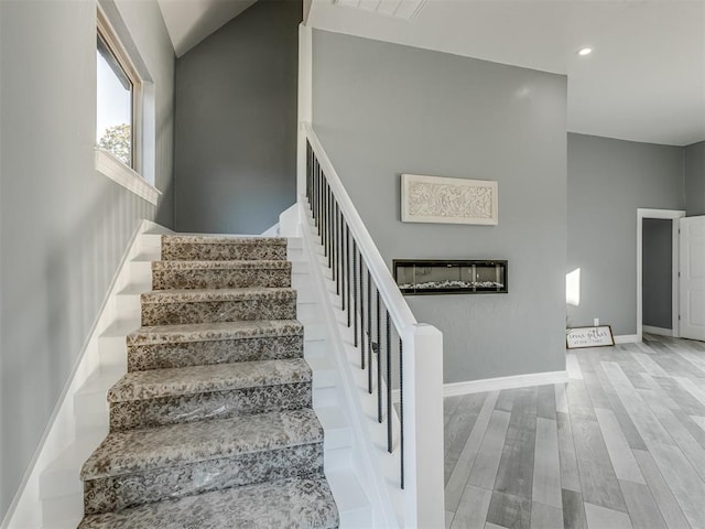 stairs with hardwood / wood-style floors and vaulted ceiling