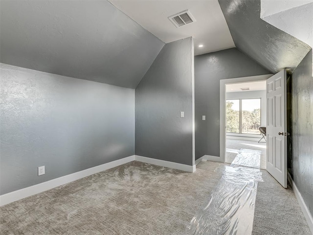 bonus room with light colored carpet and vaulted ceiling