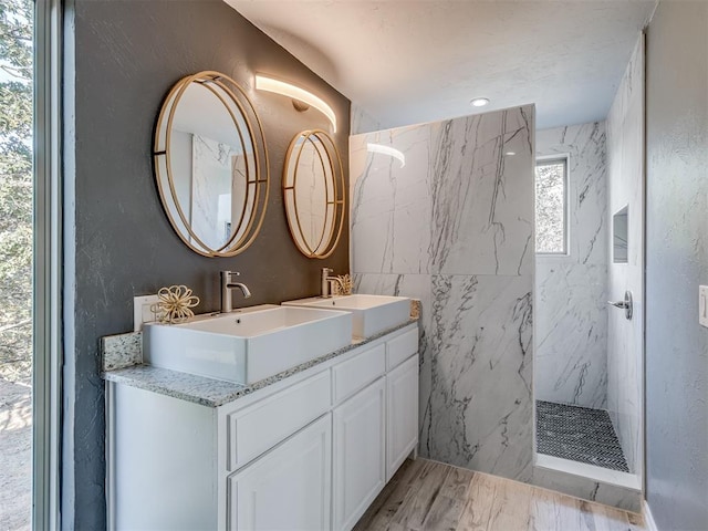 bathroom with hardwood / wood-style floors, vanity, and a tile shower