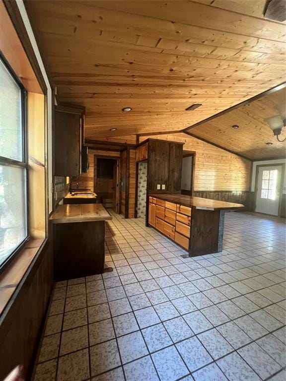 kitchen featuring lofted ceiling, a breakfast bar, wooden ceiling, and wood walls